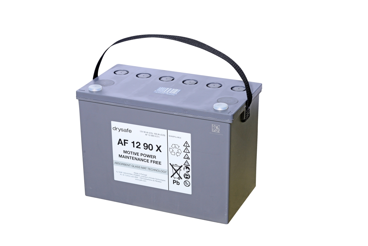 Grey, rectangular ‘ Exide ’ Sonnenschein traction battery AF 12 90 X with black carrying handle. Front label: ‘drysafe MOTIVE POWER MAINTENANCE FREE’, warning symbols including ‘Pb’. Sealing caps and terminals on top. 12V 90Ah maintenance-free.