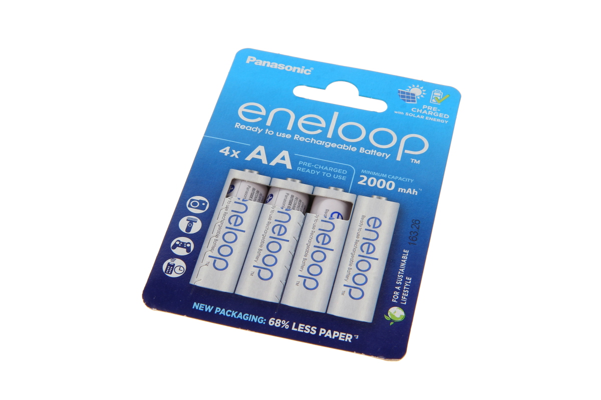 Cuatro pilas recargables eneloop AA NiMH blancas Panasonic en blíster azul. «Ready to use» y «PRE-CHARGED», 2000 mAh. El embalaje muestra una cámara y un mando, e indica «New Packaging» con menos papel.