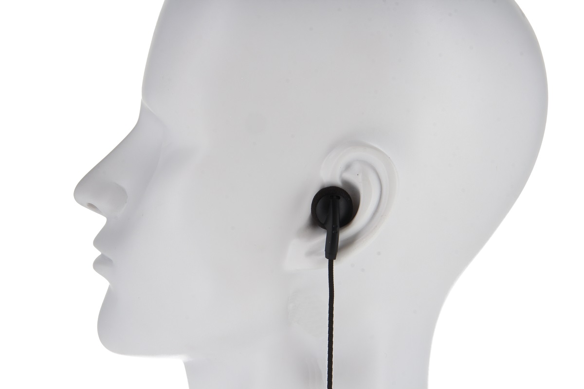 A white mannequin’s head, seen in profile from the left. A black in-ear headphone fits snugly in the right ear, with the cable running vertically downwards. The focus is on how it sits on the ear. Specially designed for control units.