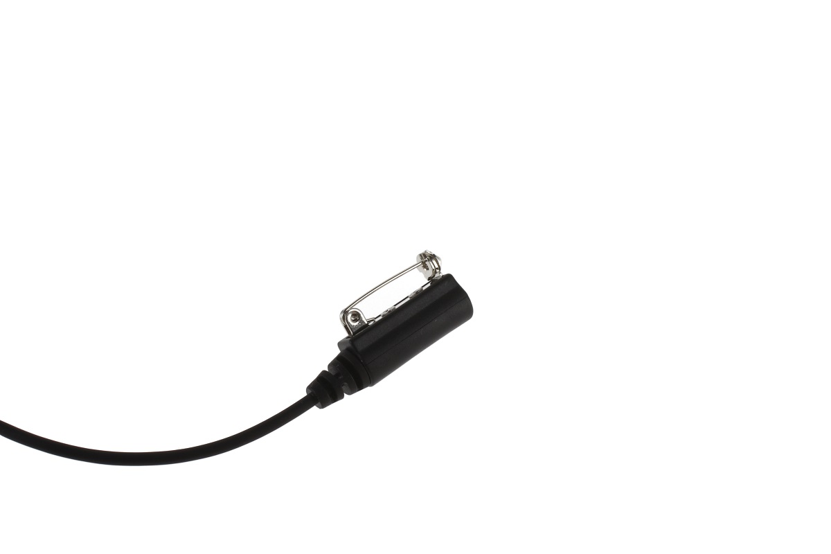 Primer plano de un mini micrófono de solapa negro o botón PTT independiente con un clip metálico plateado para sujetarlo a la ropa. Un cable negro sale por la parte inferior; forma parte de un auricular CoPacks para equipos de radio Sepura.