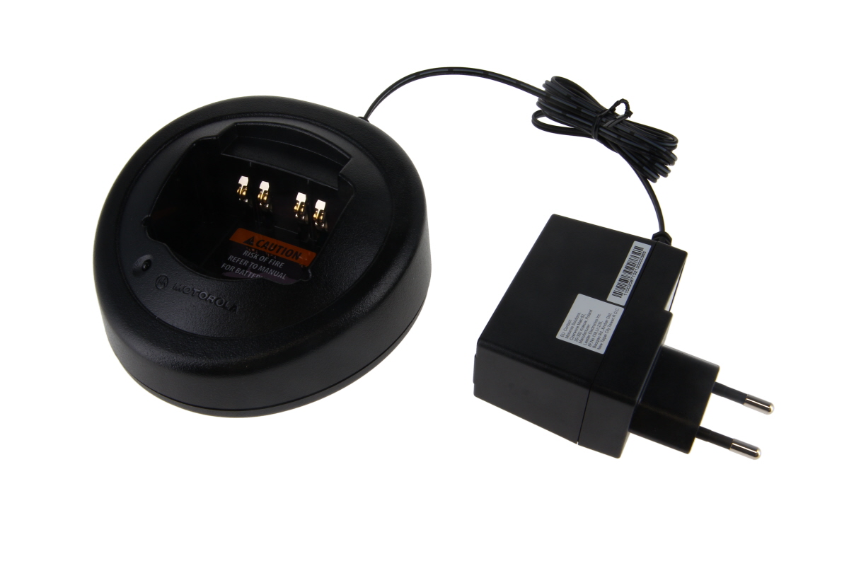 Cargador Motorola, negro y ovalado, de 1 ranura, con bandeja de carga redonda, 4 contactos dorados y adaptador de corriente de la UE conectado mediante cable. En la bandeja hay una etiqueta de advertencia de color naranja. Para GP320, GP330, GP340.