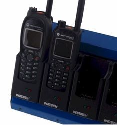 Primer plano de un cargador de 6 ranuras azul « Wetech » con dos radios Tetra « Motorola » (MTP850, MTH800) de color negro en proceso de carga. Cada ranura muestra el logotipo « Wetech », así como indicadores de estado rojos y verdes.