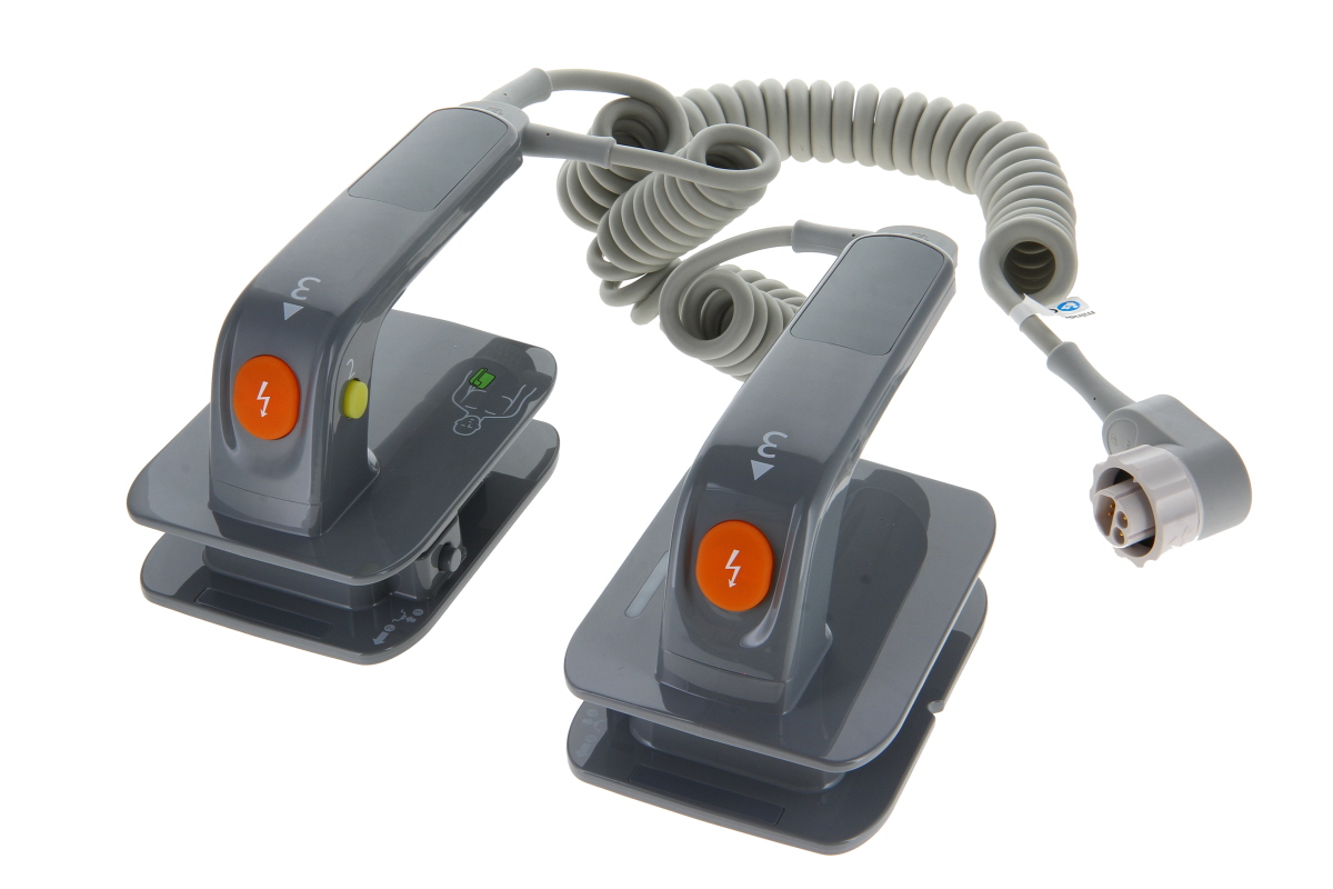 Zwei graue Defibrillator-Paddles sind mit einem spiralförmigen, hellgrauen Kabel verbunden. Jedes hat einen orangefarbenen Blitzknopf und eine grüne Anzeige; eines zeigt eine Skizze zur Elektrodenplatzierung. Freigestellt auf Weiß.