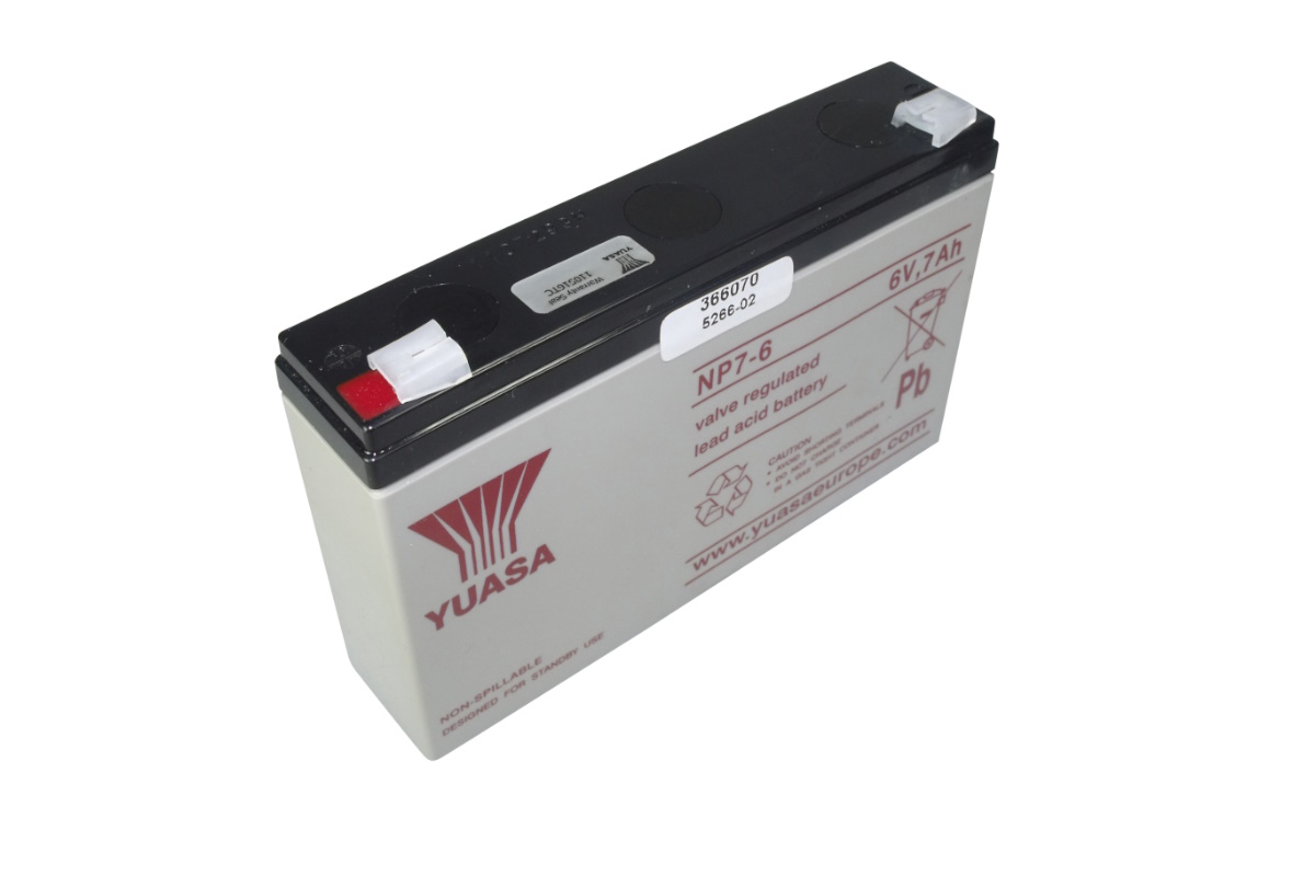 Grey, rectangular Yuasa lead-glass fibre mat battery NP7-6 with a black top. Front: Yuasa logo, NP7-6, 6V, 7Ah, ‘valve-regulated lead-acid battery’. Two terminals on top, red and white.