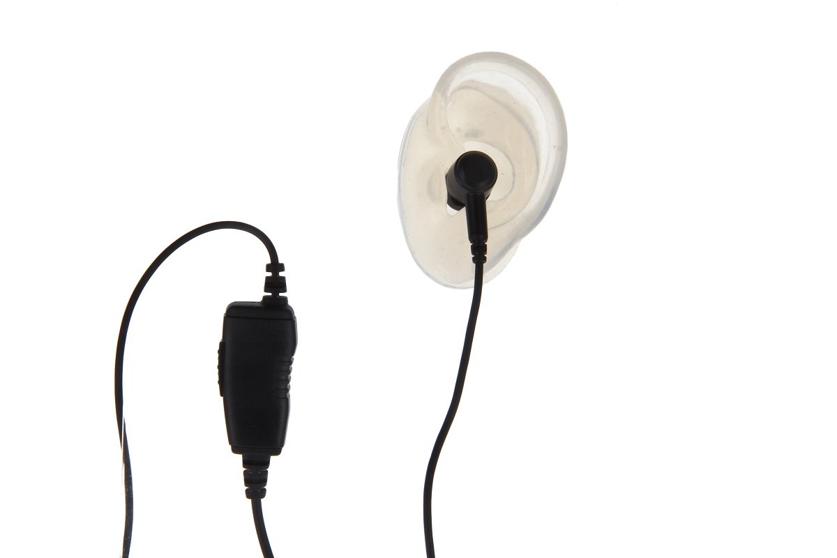 CoPacks Cuffie GES-PA1 con auricolare nero in gommino trasparente e anatomico. Accanto, il pulsante PTT in linea nero e allungato con superficie zigrinata. Cavi neri su sfondo bianco.