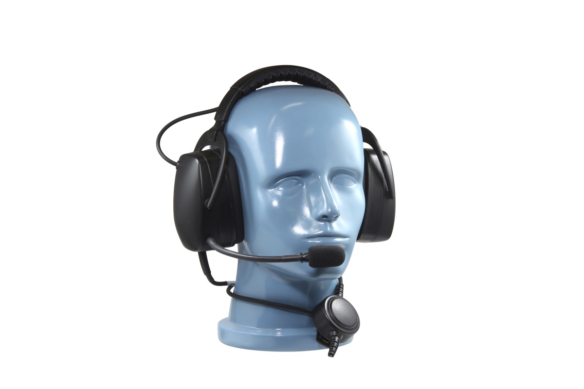 Robust, svart over-ear hörselskyddsheadset med brett huvudband och stora öronkåpor på ett ljusblått mannekänghuvud. Flexibel mikrofonbom framför munnen, rund inline PTT på vänster öronkåpa.