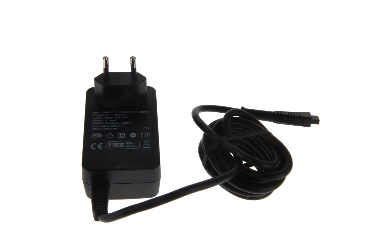 Schwarzes Steckernetzteil NA3000-2 mit zwei runden Metallstiften. Schwarzes, aufgerolltes Kabel mit viereckigem Stecker. Etikett zeigt Ein-/Ausgangsspannungen, Modell "Typ 73441101", Herstellerinfos und Zertifizierungen.