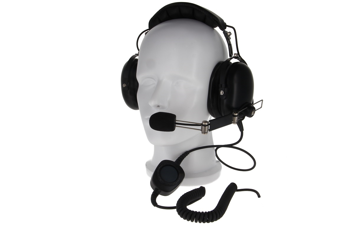 Svart, robust pilotheadset på vitt mannekänghuvud. Stora, vadderade öronkåpor, justerbar bommikrofon med vindskydd. Svart spiralkabel till den runda push-to-talk-enheten för Motorola radioapparater.