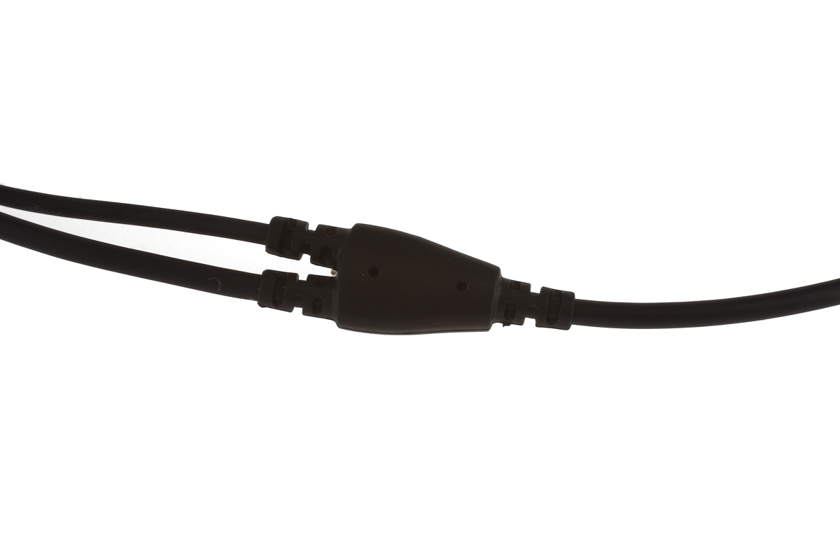 Cable divisor en Y negro de unos auriculares. Dos cables más finos conducen a un conector ovalado negro, del que sale un único cable más grueso para la conexión con la radio. Vista detallada de la división del cable.