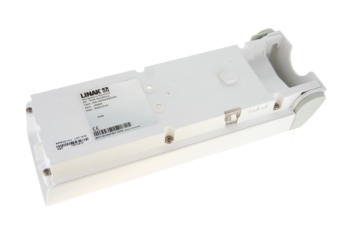 Vit, långsträckt Linak batterilåda BAL40, snett uppifrån mot vit bakgrund. Ovansidan med fördjupningar, två silverfärgade skruvar och stor etikett (Linak logotyp, typ BAL40D6AZ900000, streckkod). Grå ändlock till höger.