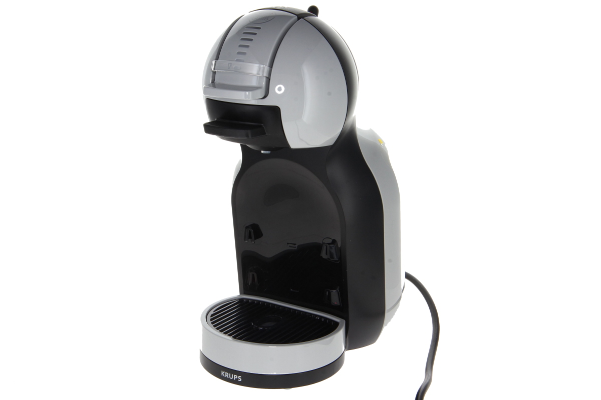 Krups Nescafé Dolce Gusto kapselmaskin i färgerna artic grey/black, diagonalt framifrån höger. Svängd kropp med ljusgrått huvud och svart mittparti. Rund, justerbar droppbricka med galler och KRUPS-logotyp längst ner. Kabel på höger sida.