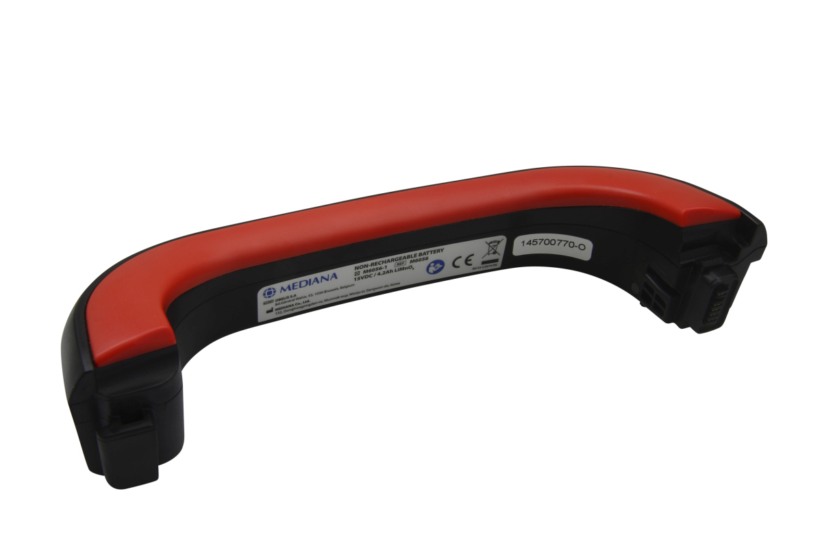 Långsträckt, böjt engångsbatteri av typen Mediana, svart med rött, ergonomiskt handtag. På det svarta höljet: modell M6056-1, 15 VDC/4,2 Ah LiMnO2, CE och serienummer 145700770-O. Med anslutningskontakt.