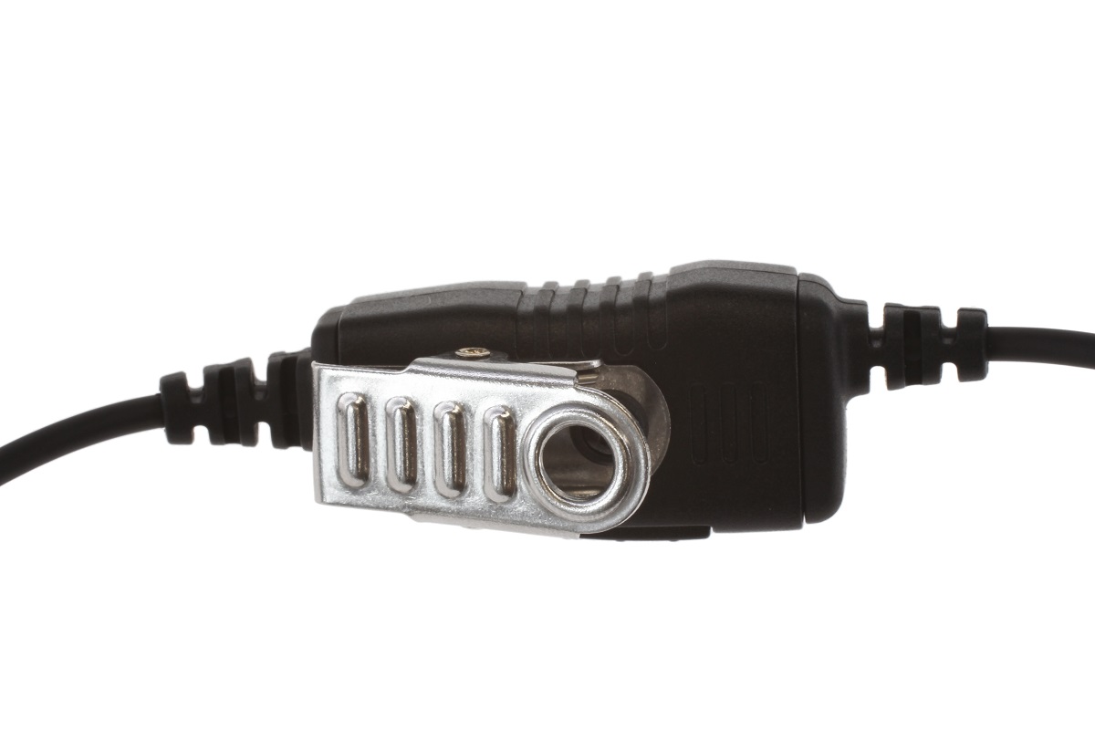 Primer plano de una unidad PTT (Push-to-Talk) negra con un clip metálico plateado para su fijación. Conectada por ambos extremos con cables negros; componente central de un kit de comunicación CoPacks para las series SL y los auriculares de Motorola.