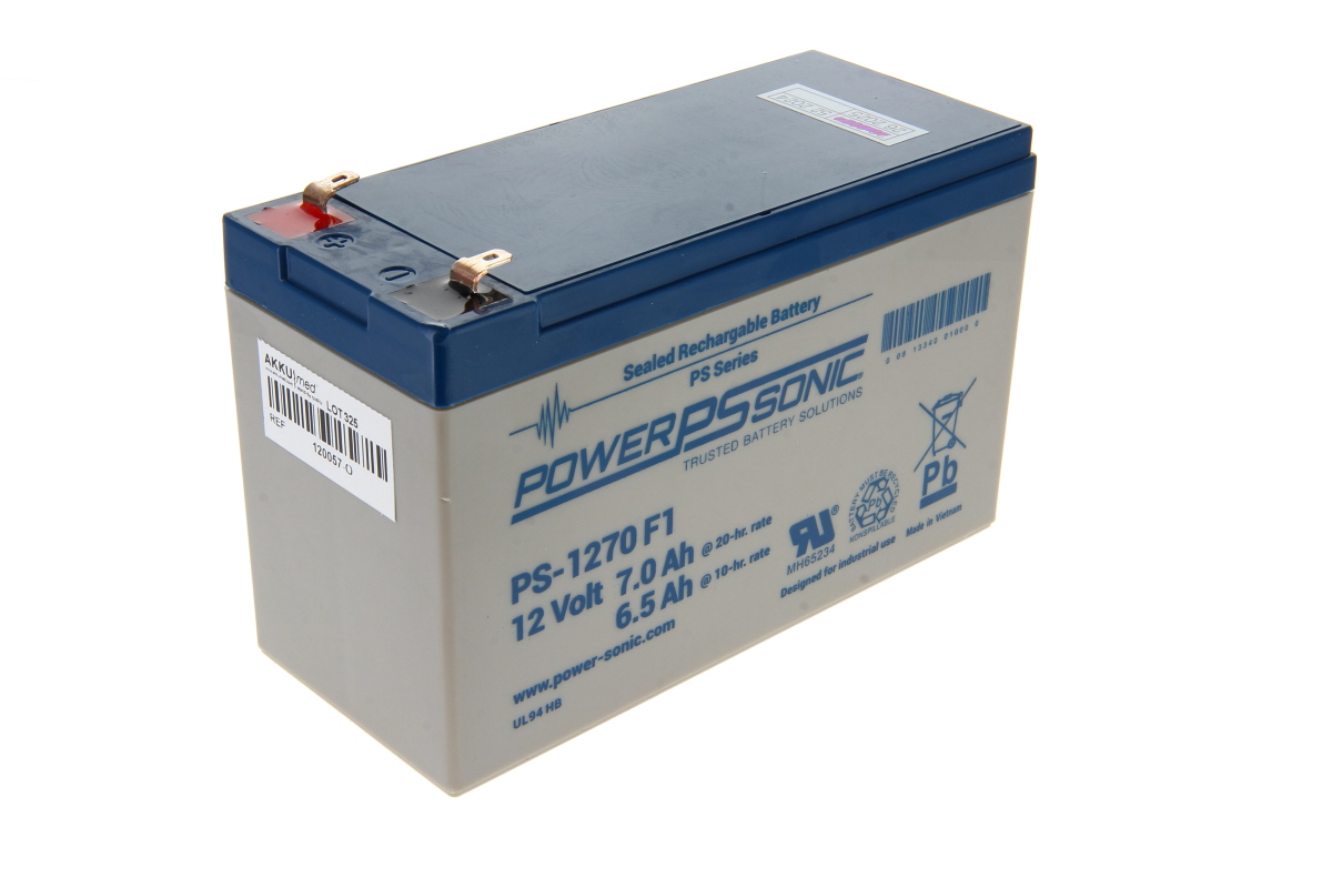 Grått, rektangulärt Power-Sonic blybatteri med mörkblå topp och två kopparplintar. Etikett: PS-1270 F1, 12 Volt 7,0 Ah. Certifieringssymboler, återvinning och Pb till höger; streckkodsetikett AKKUMED till vänster.