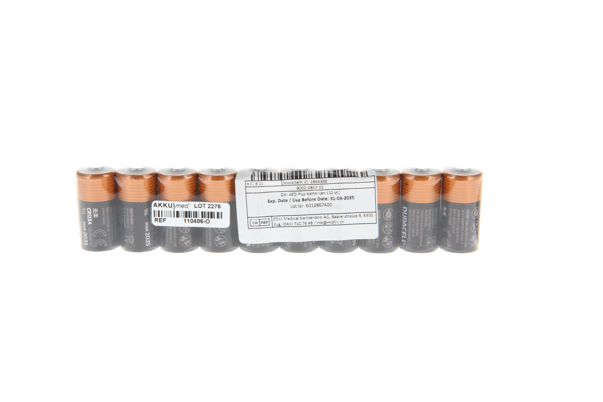 Diez pilas CR123A de Duracell, en un envase transparente. Cilíndricas, de color gris oscuro con los extremos naranjas. En el centro, una etiqueta blanca con detalles, entre otros: «Zoll, pilas para AED Plus (10 uds.)» y fecha de caducidad: 31/03/2035.