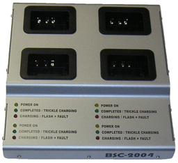Cargador cuádruple plateado con cuatro ranuras negras para dispositivos móviles de captura de datos. Bajo cada ranura, LED verdes, amarillos y rojos indican el estado de carga. Carcasa de aluminio con «BSC-2004», carga baterías a la vez.