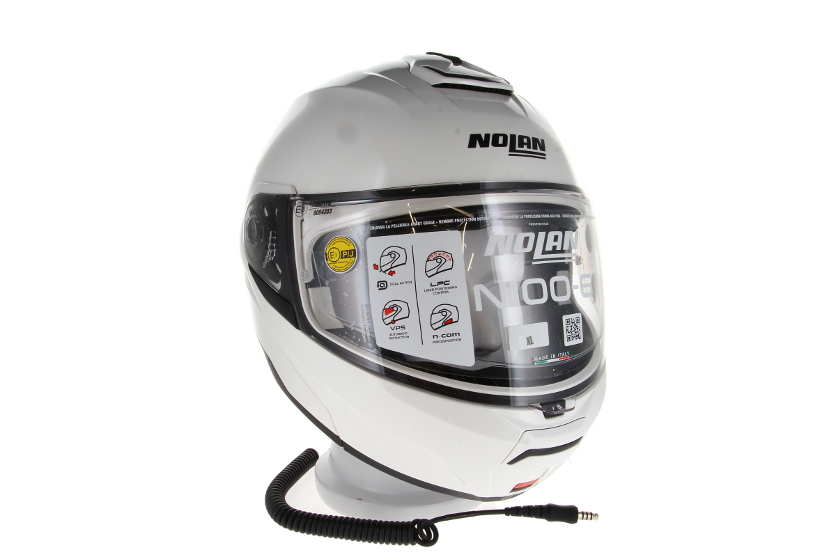 Weißer Nolan N100-6 Klapphelm für Motorradfahrer, von vorne leicht schräg. Klares Visier mit Herstellerinfos und XL-Größenangabe beklebt. Unten sichtbar: schwarzes Spiralkabel mit Nexus-Stecker fürs TITAN Helmsprechsystem.