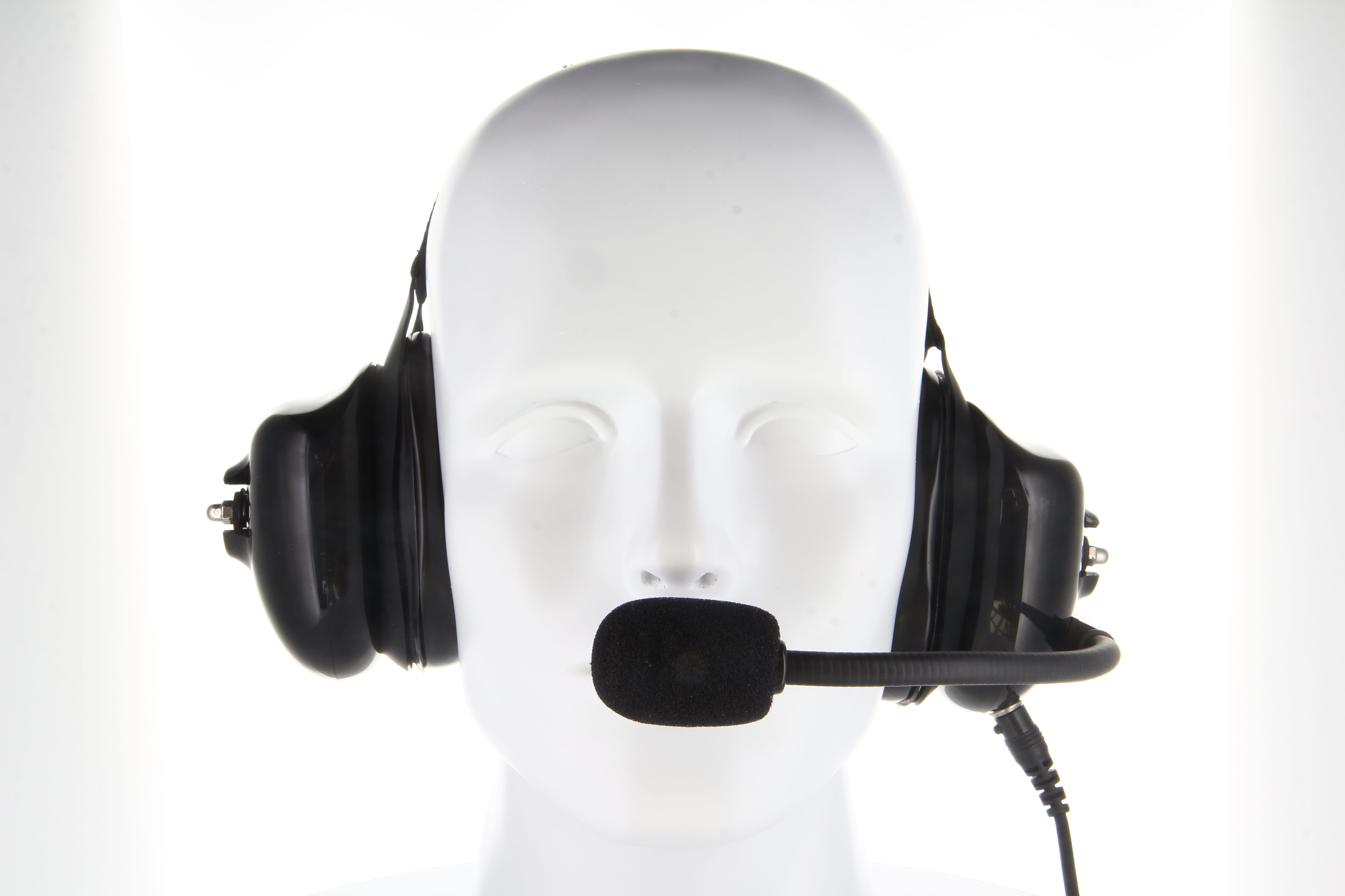 Cabeza de maniquí blanca con auriculares de piloto GES-H05 de CoPacks en color negro. Grandes almohadillas que cubren las orejas, brazo de micrófono ajustable con protección de espuma delante de la boca. Aislado sobre fondo claro.